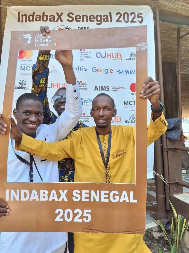 Deux participants célèbrent devant le cadre photo IndabaX Sénégal 2025