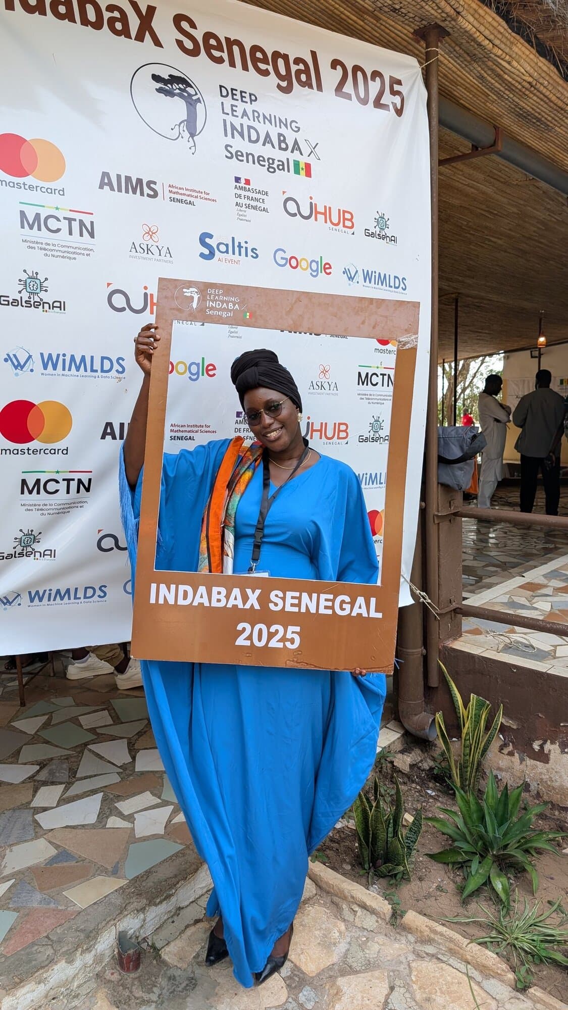 Une participante pose devant le cadre photo IndabaX Sénégal 2025